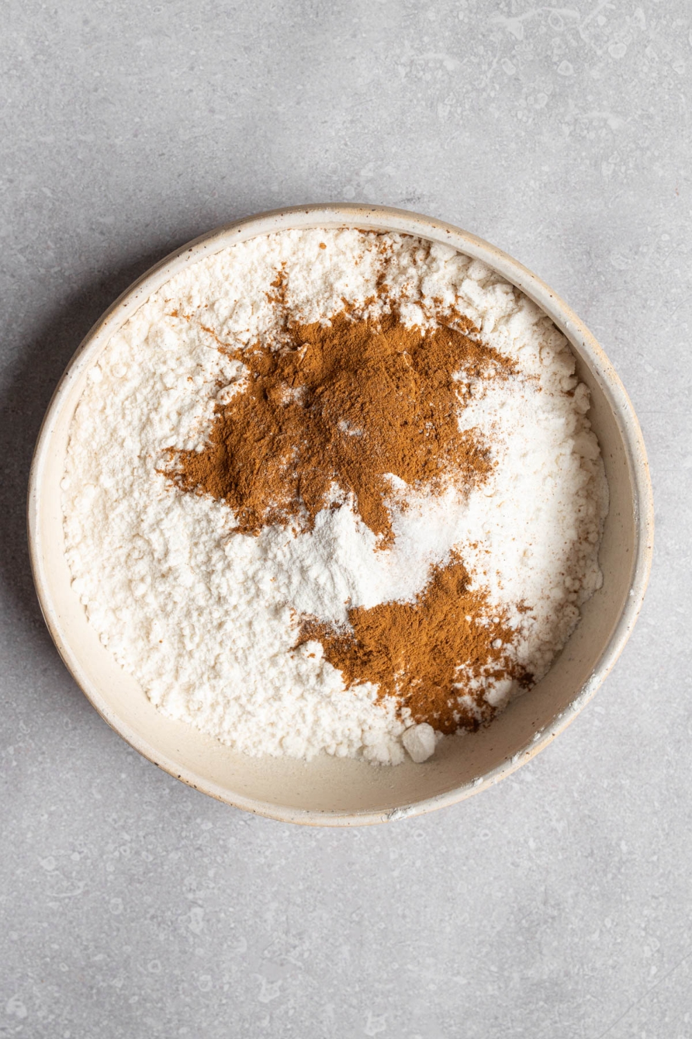 A white bowl with dry ingredients to make copycat Starbucks pumpkin muffins. The bowl is on a white counter.