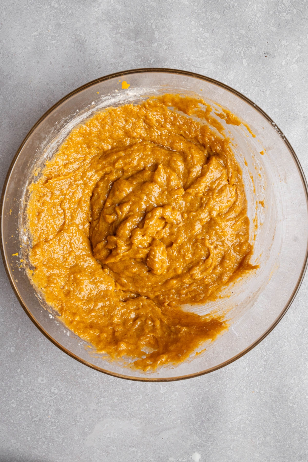 A glass bowl with mixed Starbucks pumpkin muffin batter. The bowl is on a white counter.