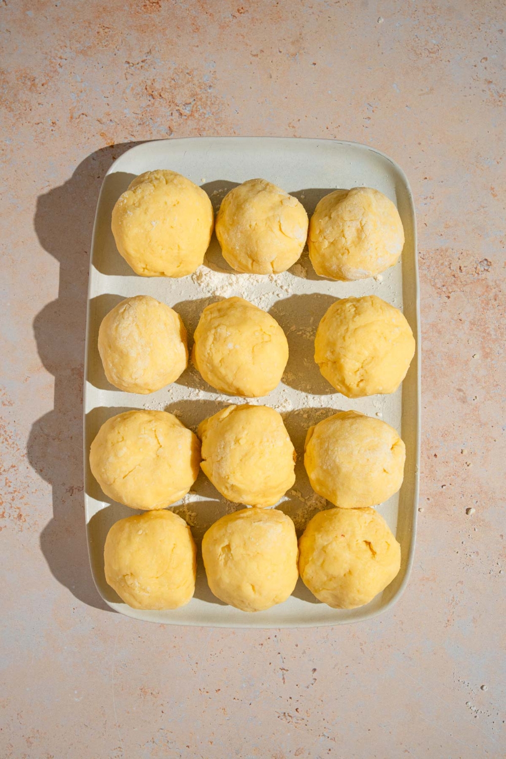 A platter with twelve pastry dough balls. The platter is on a tan counter.
