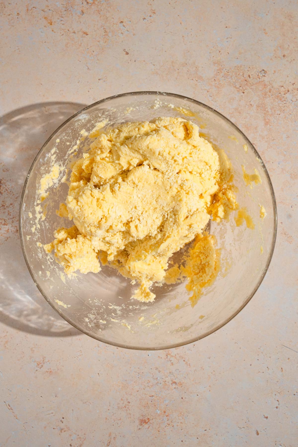A glass bowl with pastry dough. The bowl is on a tan counter.