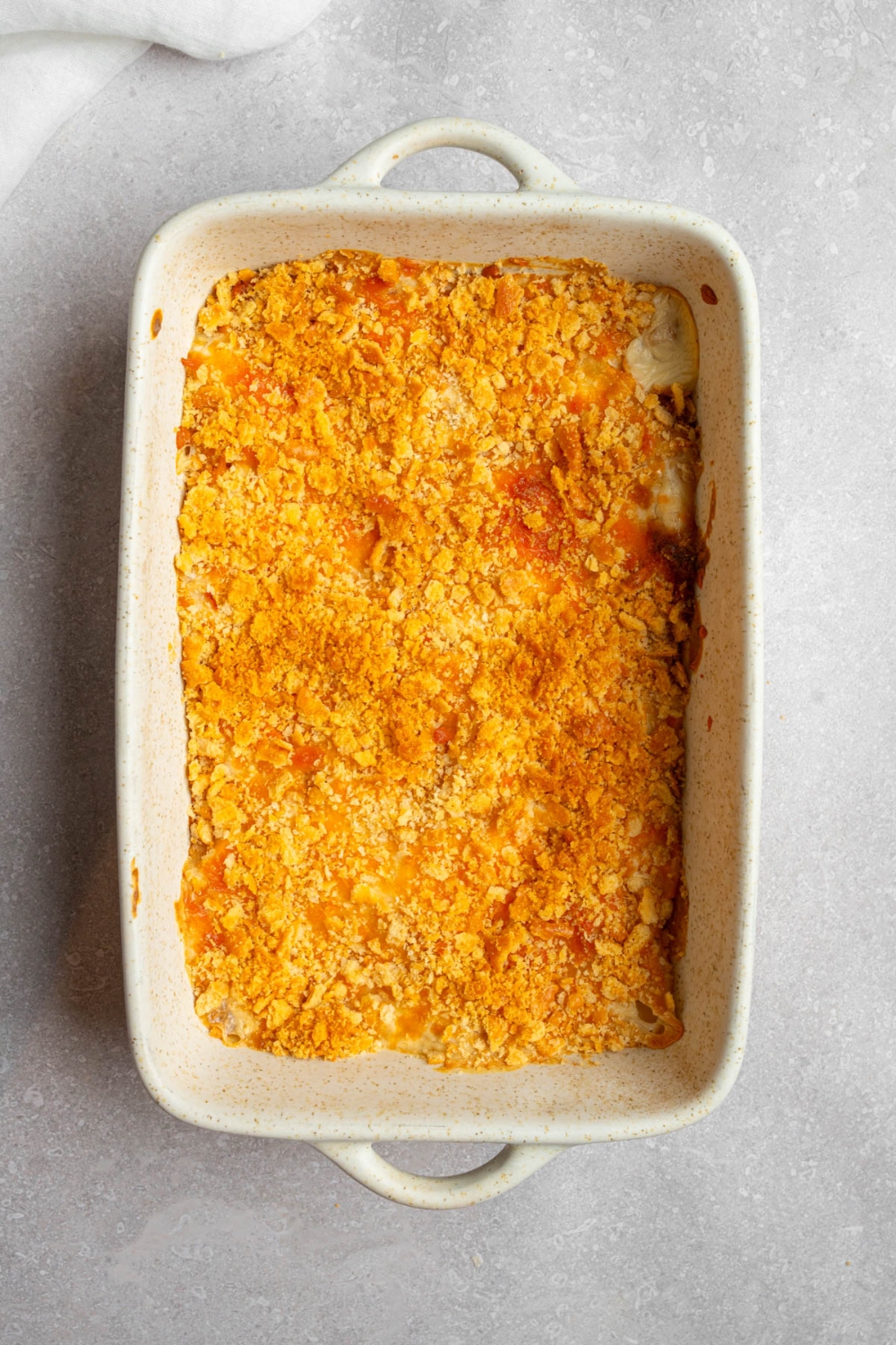 A baking dish with baked Neiman Marcus chicken casserole. The dish is on a white counter.