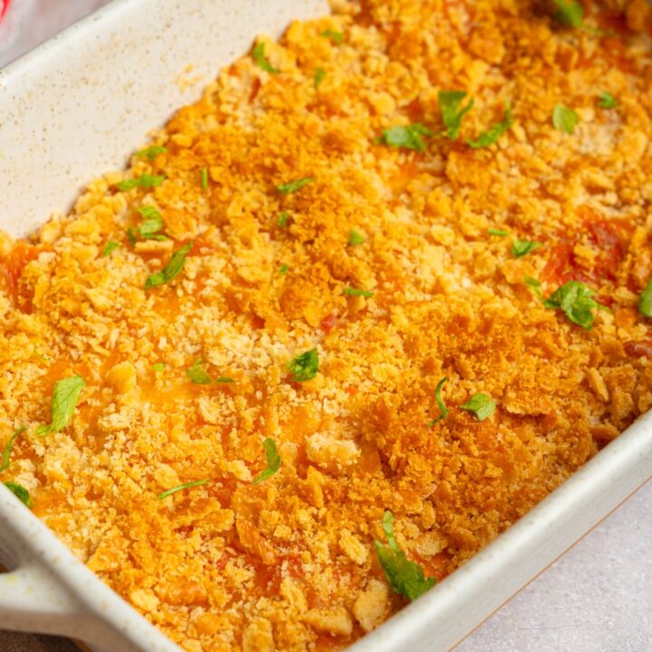 A baking dish with Neiman Marcus chicken casserole garnished with fresh parsley. The dish is on a white counter.