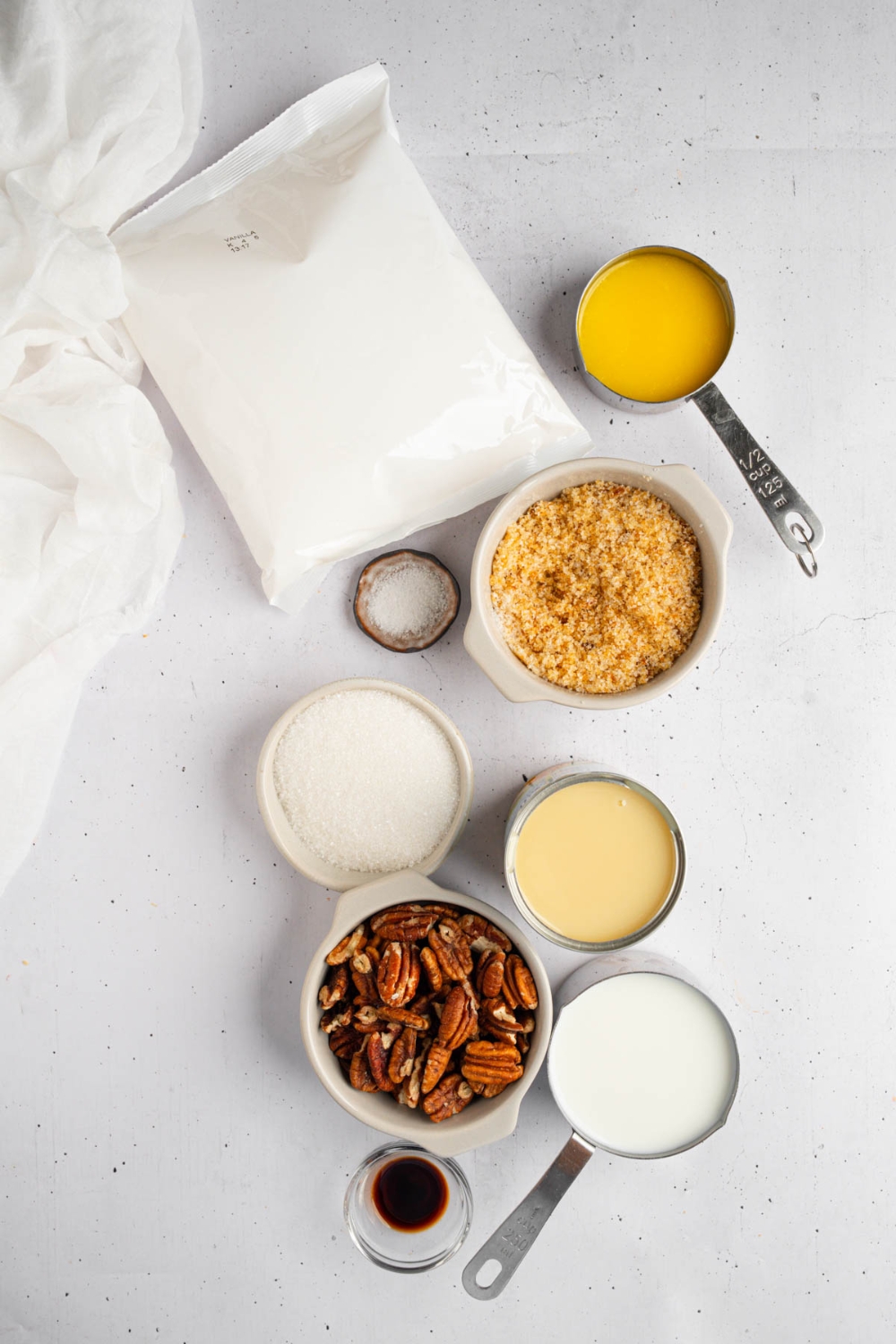 An overhead shot of several bowls in various sizes containing ingredients to make pecan pie dump cake including pecans, milk, condensed milk, butter, brown sugar, white sugar, vanilla, and cake mix.