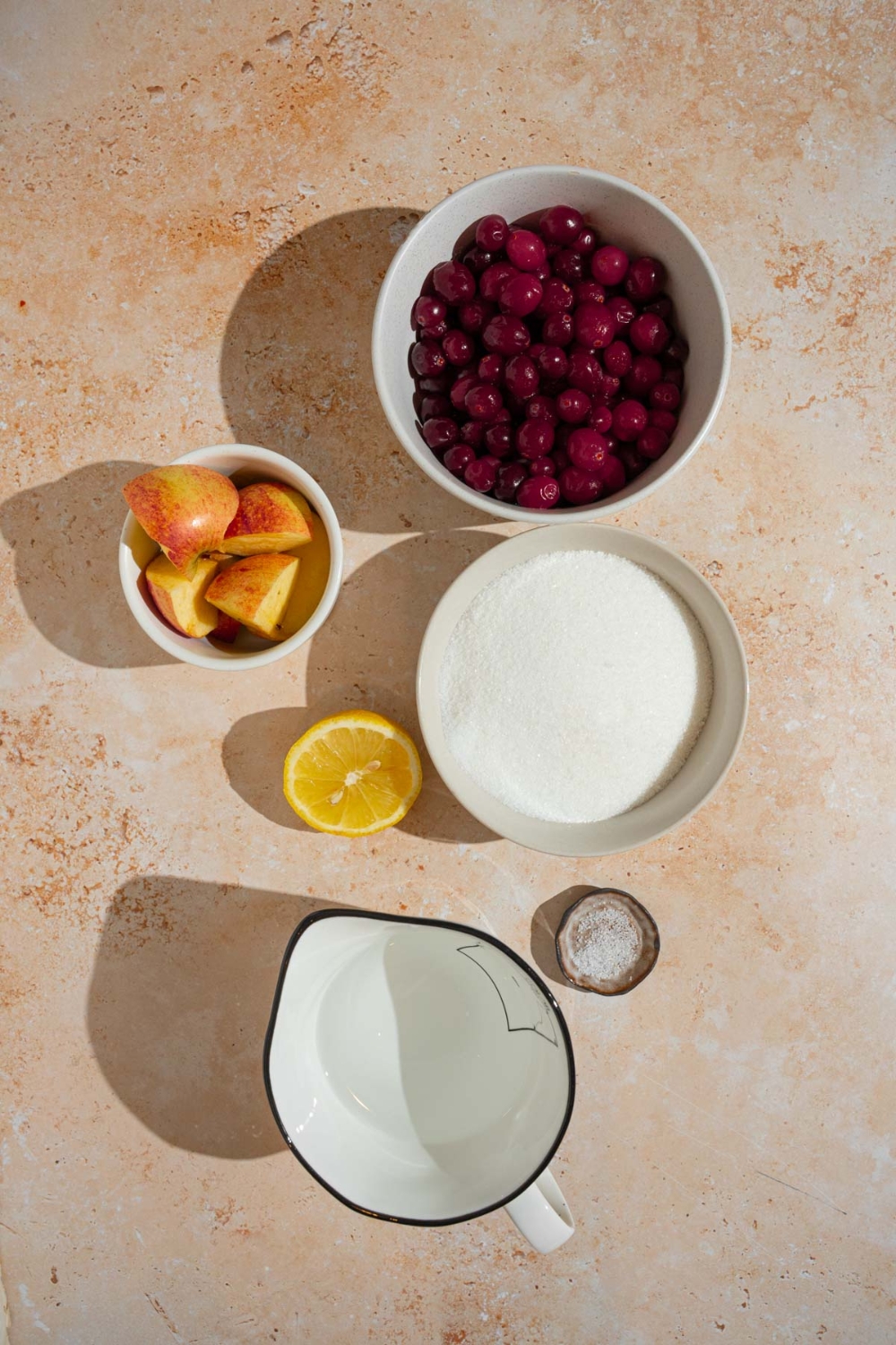 An overhead shot of ingredients to make chokecherry jelly including chokecherries, sugar, apples, water, lemon, and salt.
