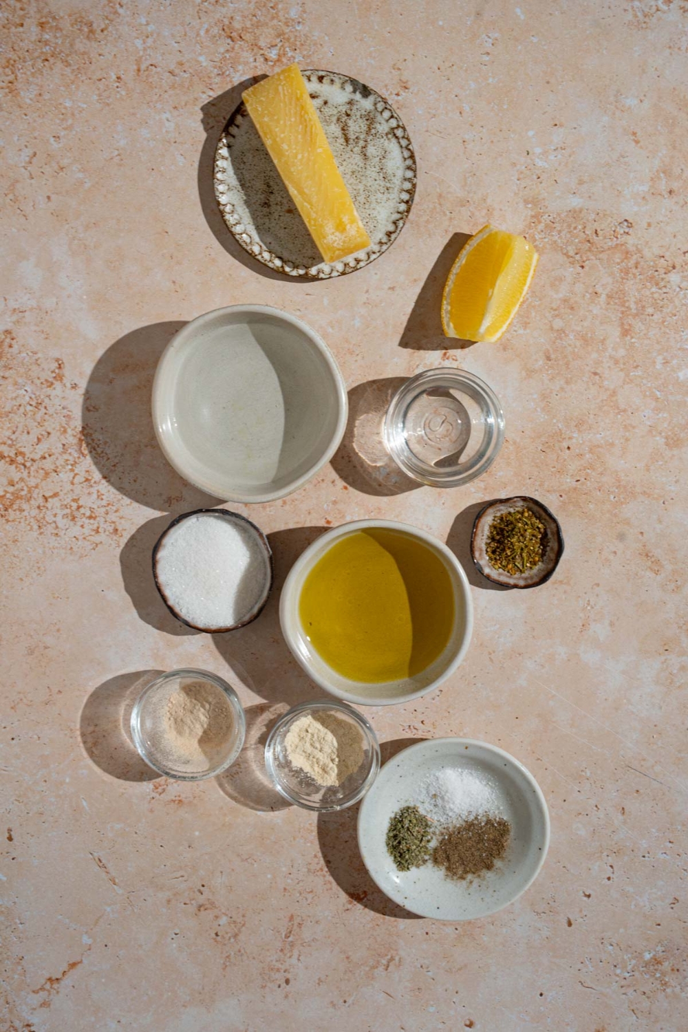 An overhead shot of several bowls in various sizes containing ingredients to make copycat Texas Roadhouse italian dressing including olive oil, vinegar, water, lemon juice, parmesan cheese, and seasonings.