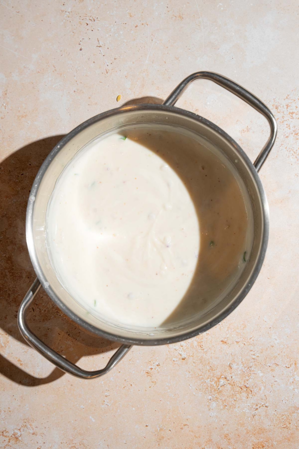 A stock pot with Chipotle queso based mixed with sour cream. The pot is on a tan counter.