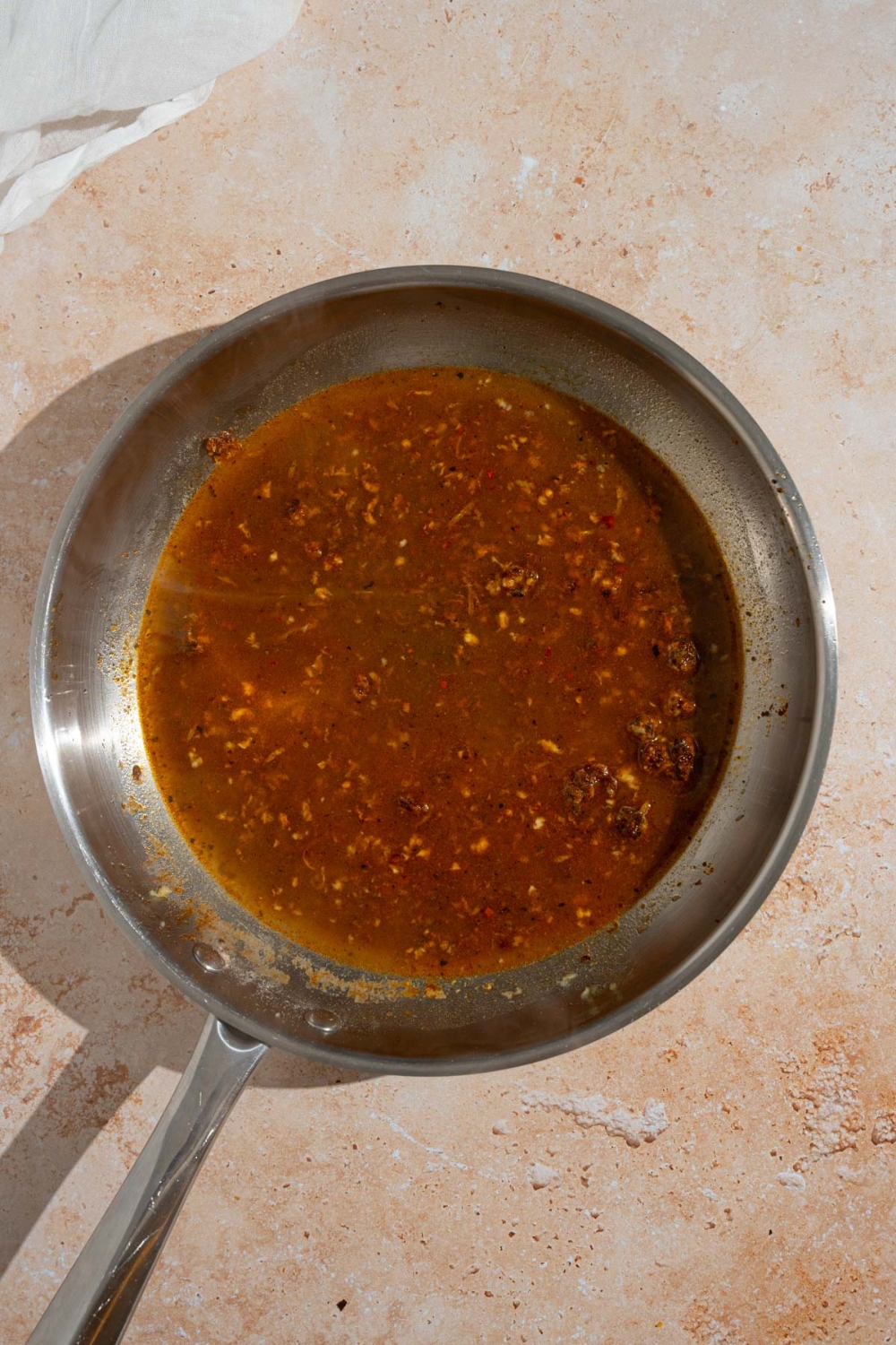 A skillet with a cooked cajun sauce mixture. The skillet is on a tan counter.