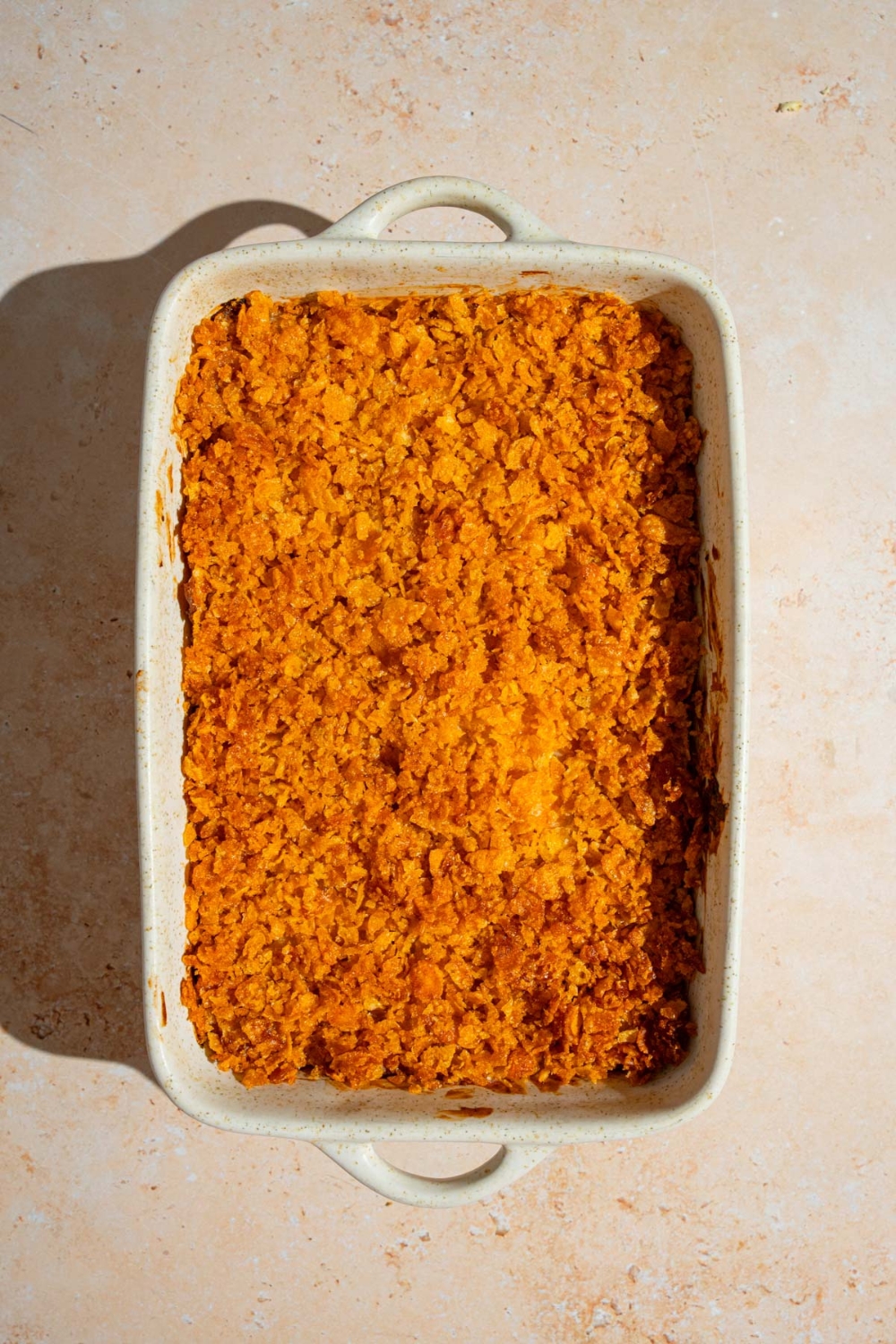 A baking dish with baked party potatoes casserole on a tan counter.