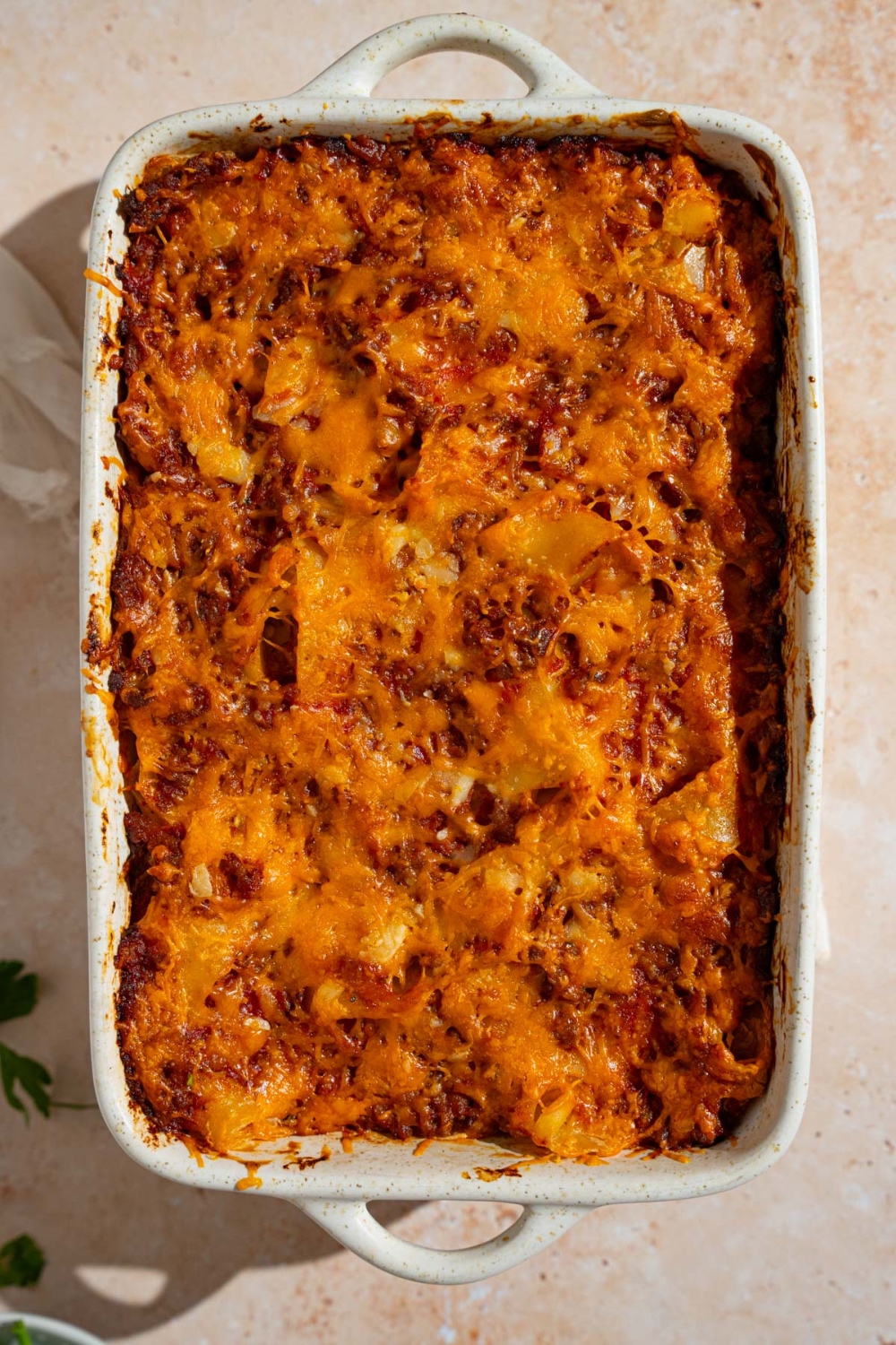 A baking dish with baked poor man's husband casserole. The dish is on a tan counter.