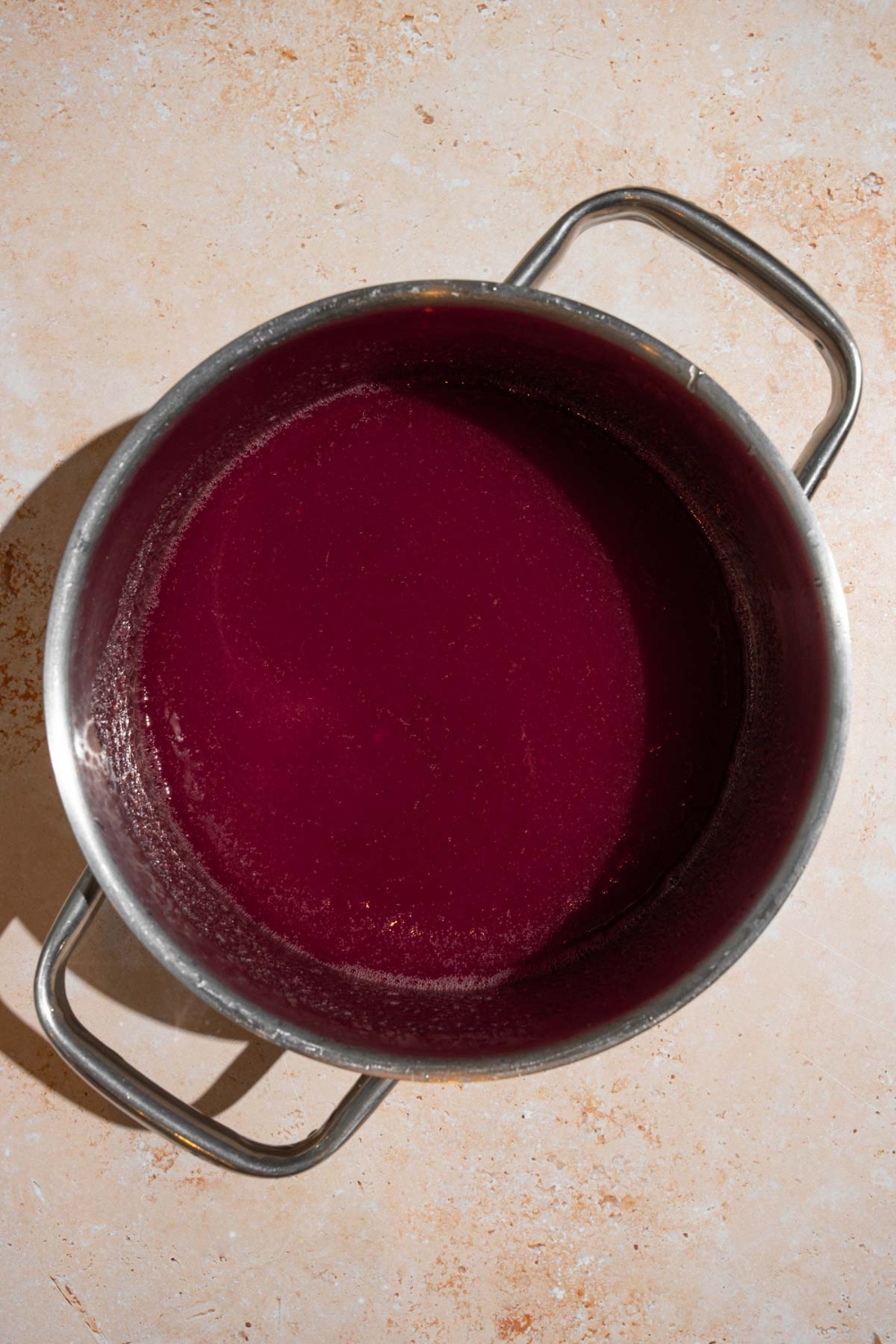 A stock pot with cooked chokecherry jelly. The pot is on a tan counter.