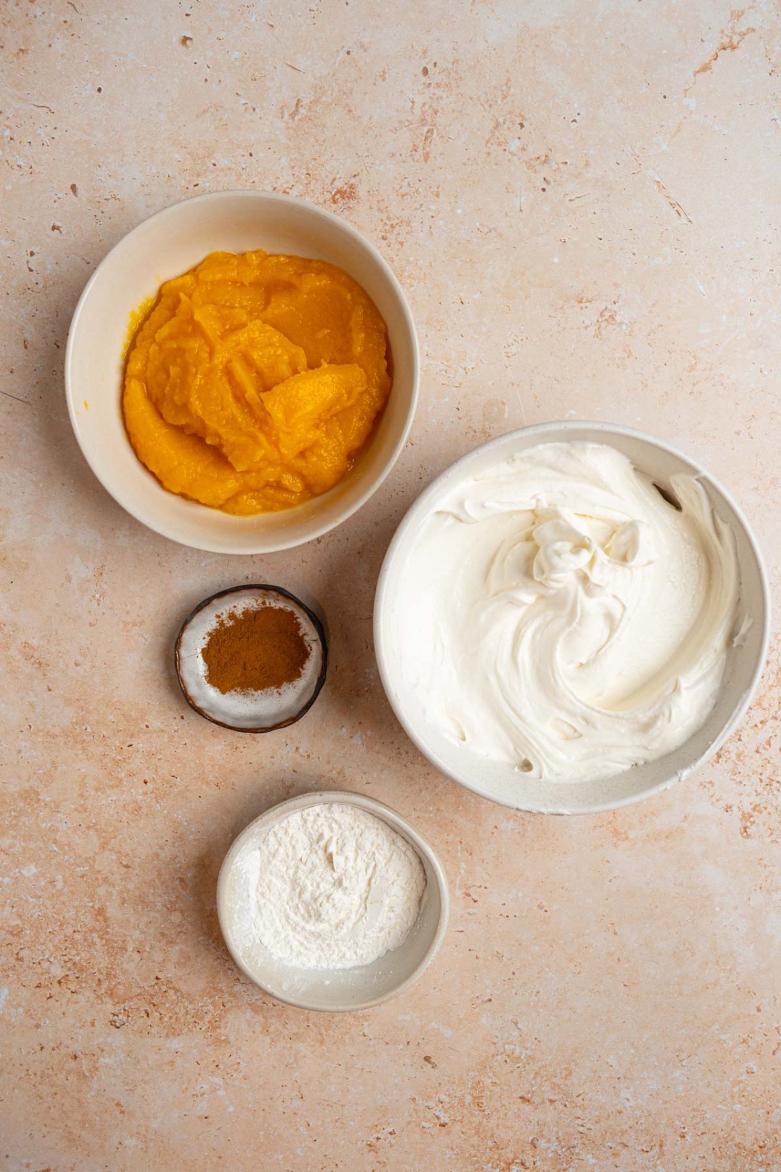 An overhead shot of several bowls with ingredients to make pumpkin fluff including pumpkin, cool whip, instant pudding mix, and pumpkin spice.
