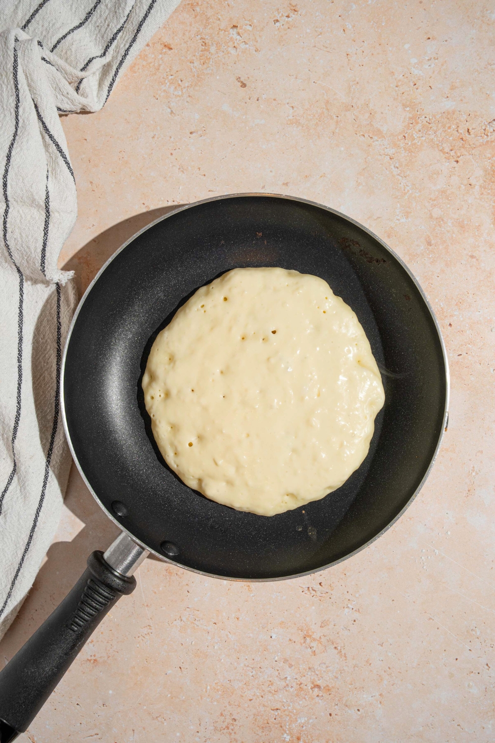 A pancake cooking and a skillet.
