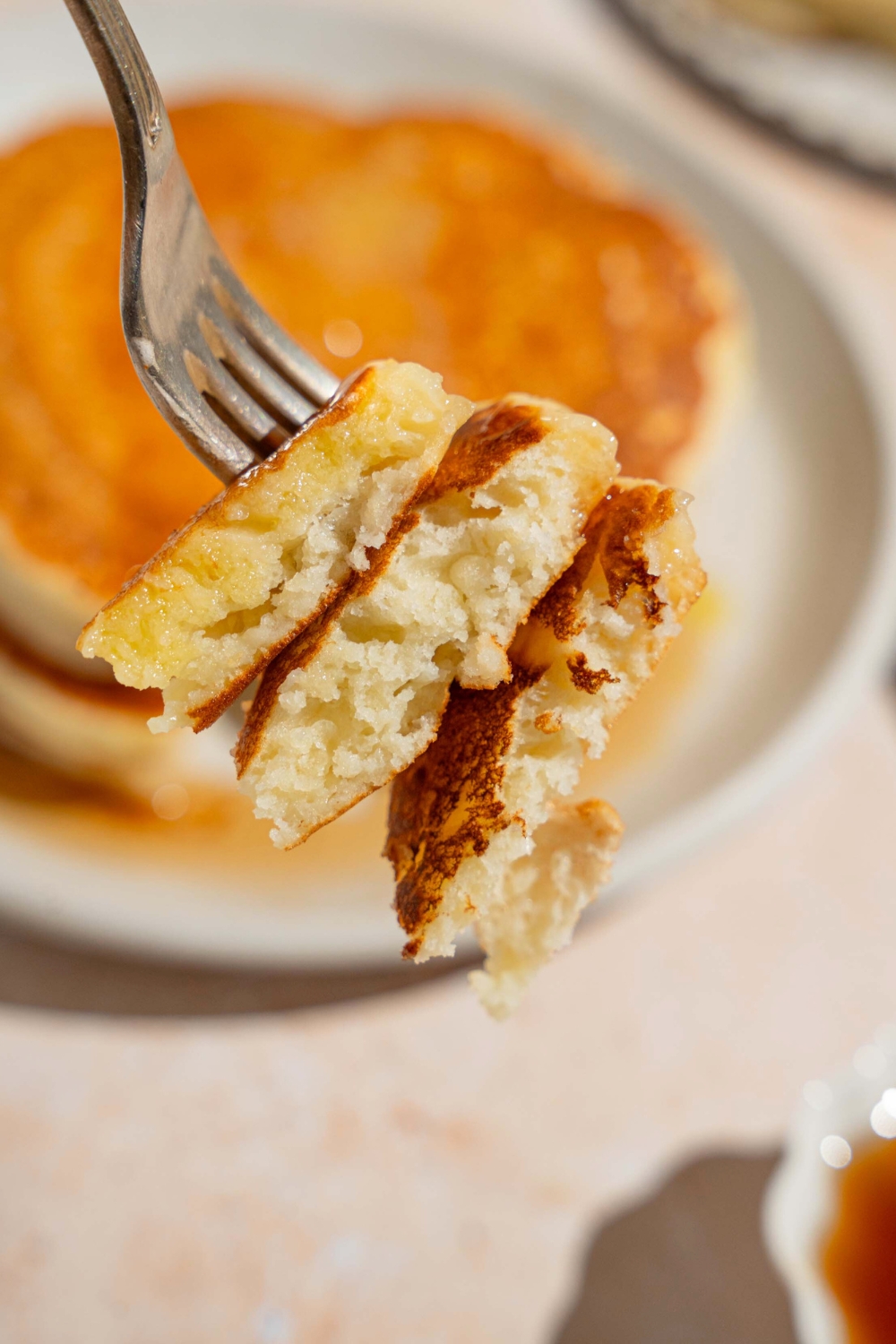 A fork with three pieces of pancake on it.