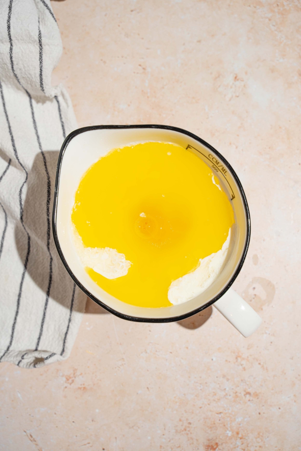 Melted butter and flour in a pitcher on top of white counter.