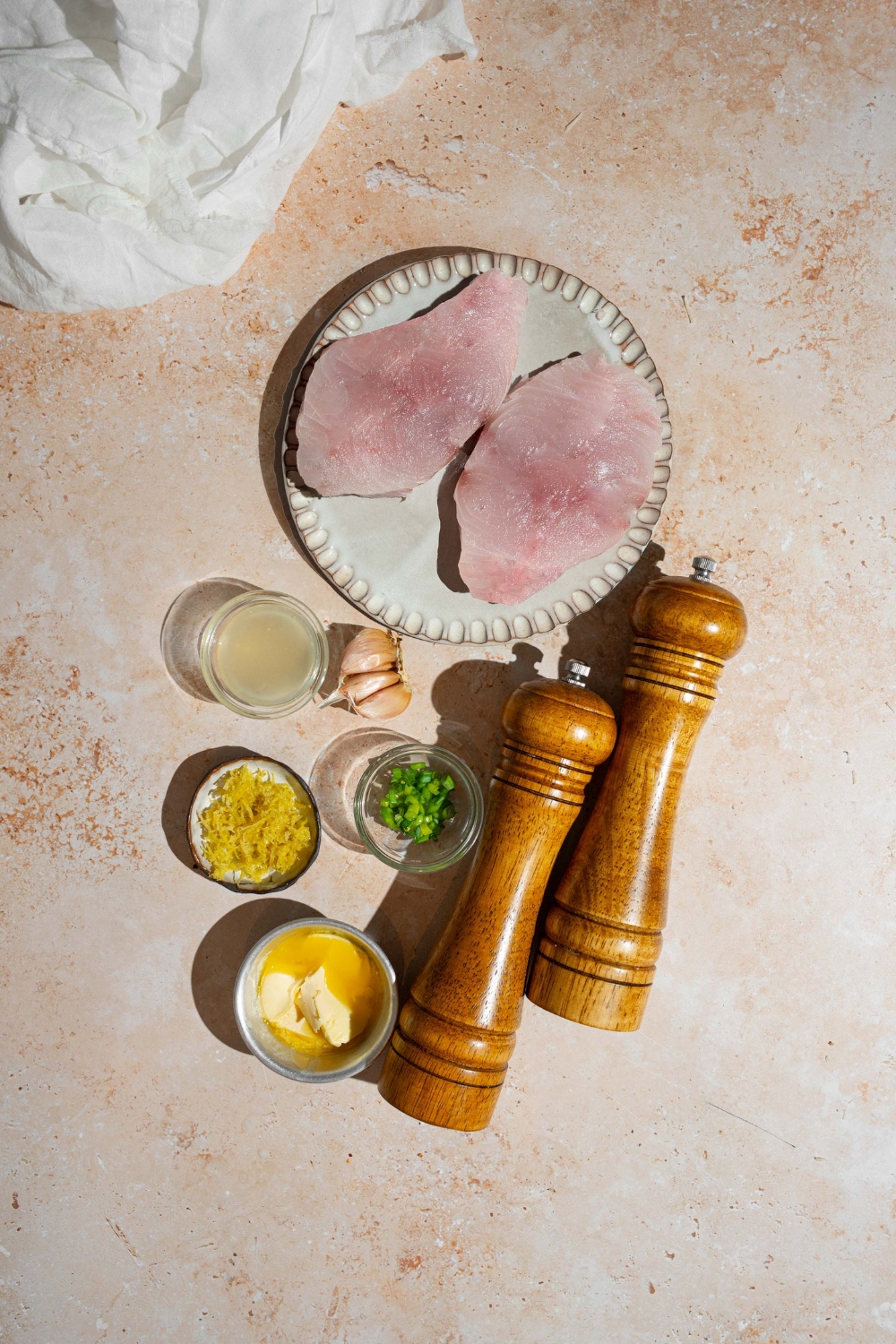 An overhead shot of ingredients to make air fryer swordfish including two swordfish fillets, lemon, butter, chives, olive oil, and seasonings.