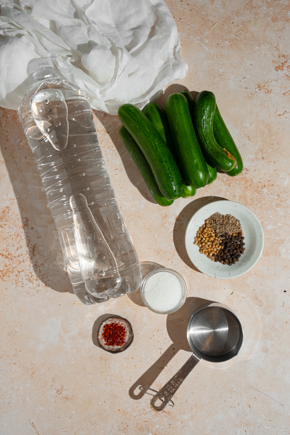 An overhead shot of ingredients to make homemade Claussen pickles including pickling cucumbers, water, vinegar, coriander seed, mustard seed, dill seed, and more.
