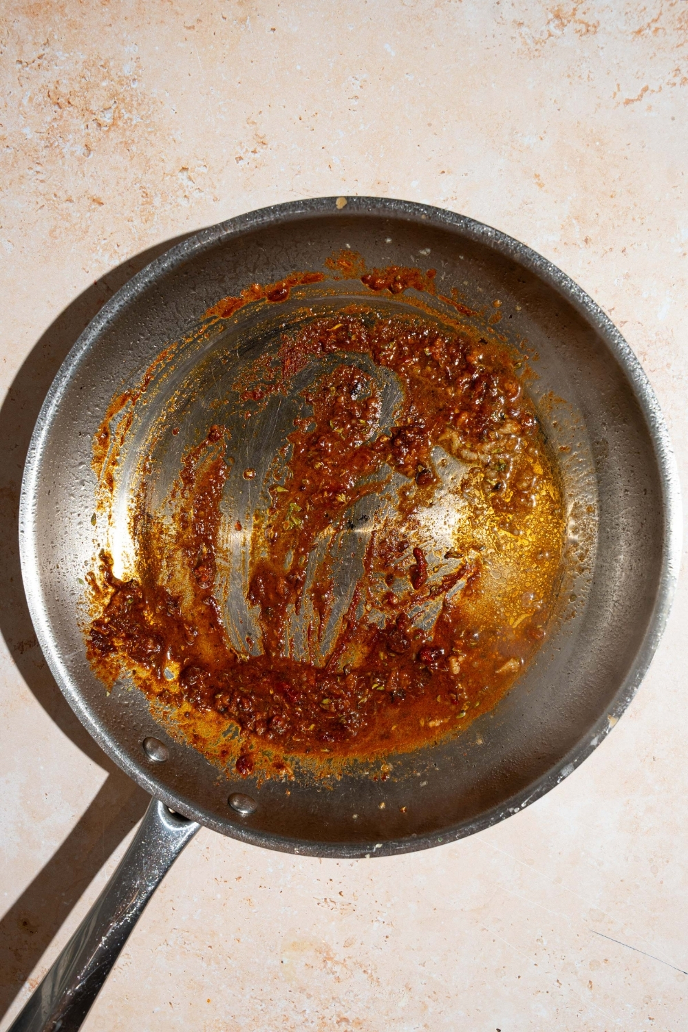 A skillet with garlic and seasonings cooking in butter. The skillet is on a tan counter.