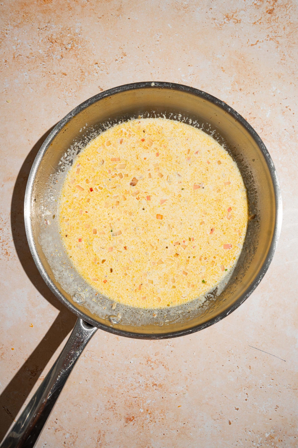 A skillet with chicken bacon ranch pasta sauce. The skillet is on a tan counter.