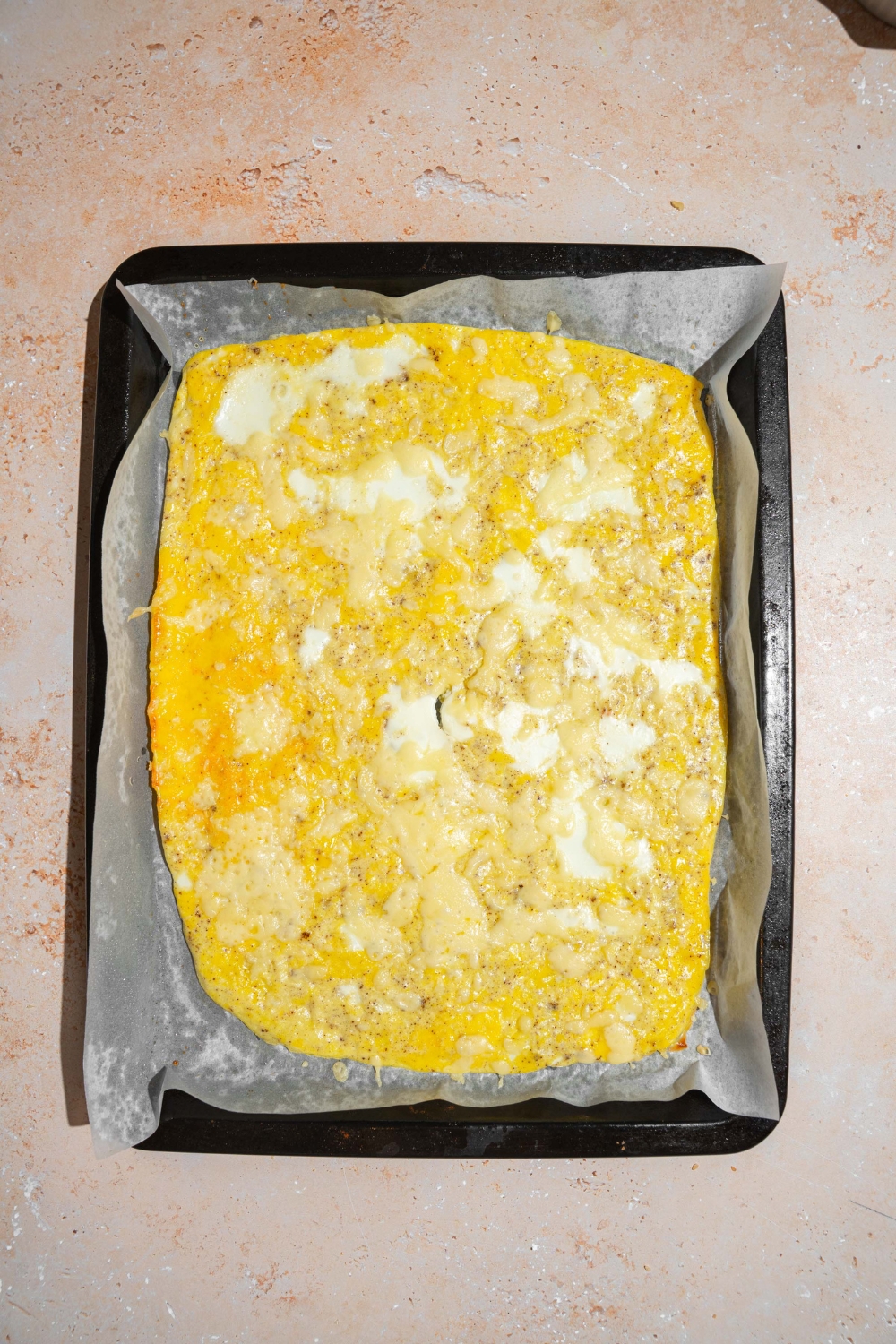 Sheet pan eggs cooked in a baking sheet lined with parchment paper. The sheet is on a tan counter.