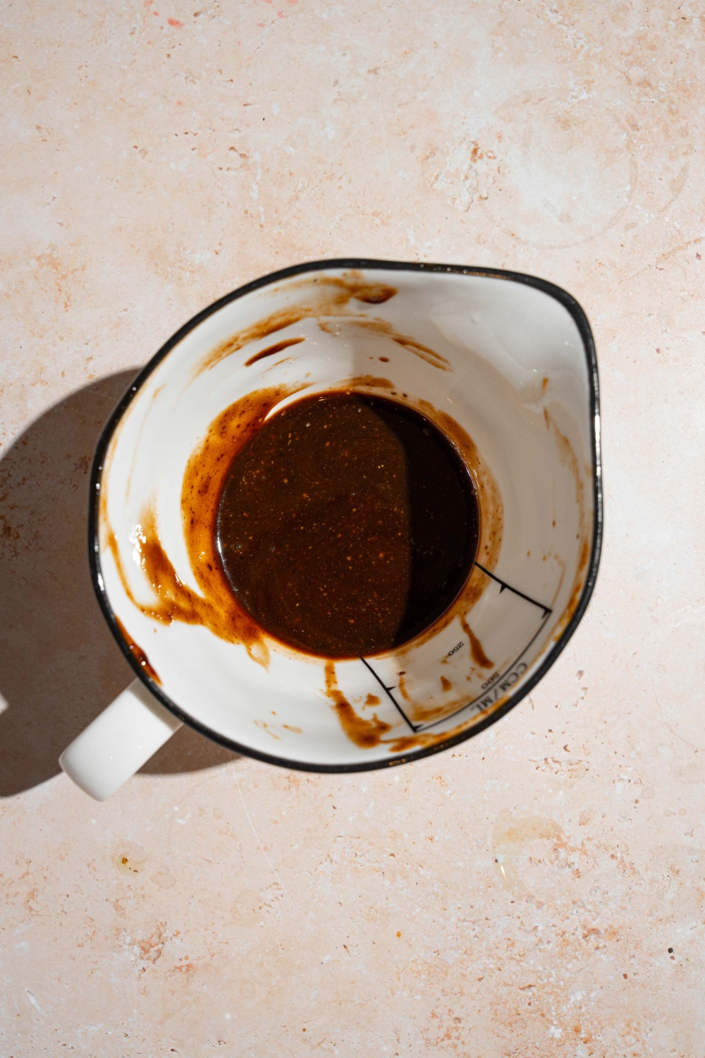 A ceramic pitcher with strained homemade A1 steak sauce. The pitcher is on a tan counter.