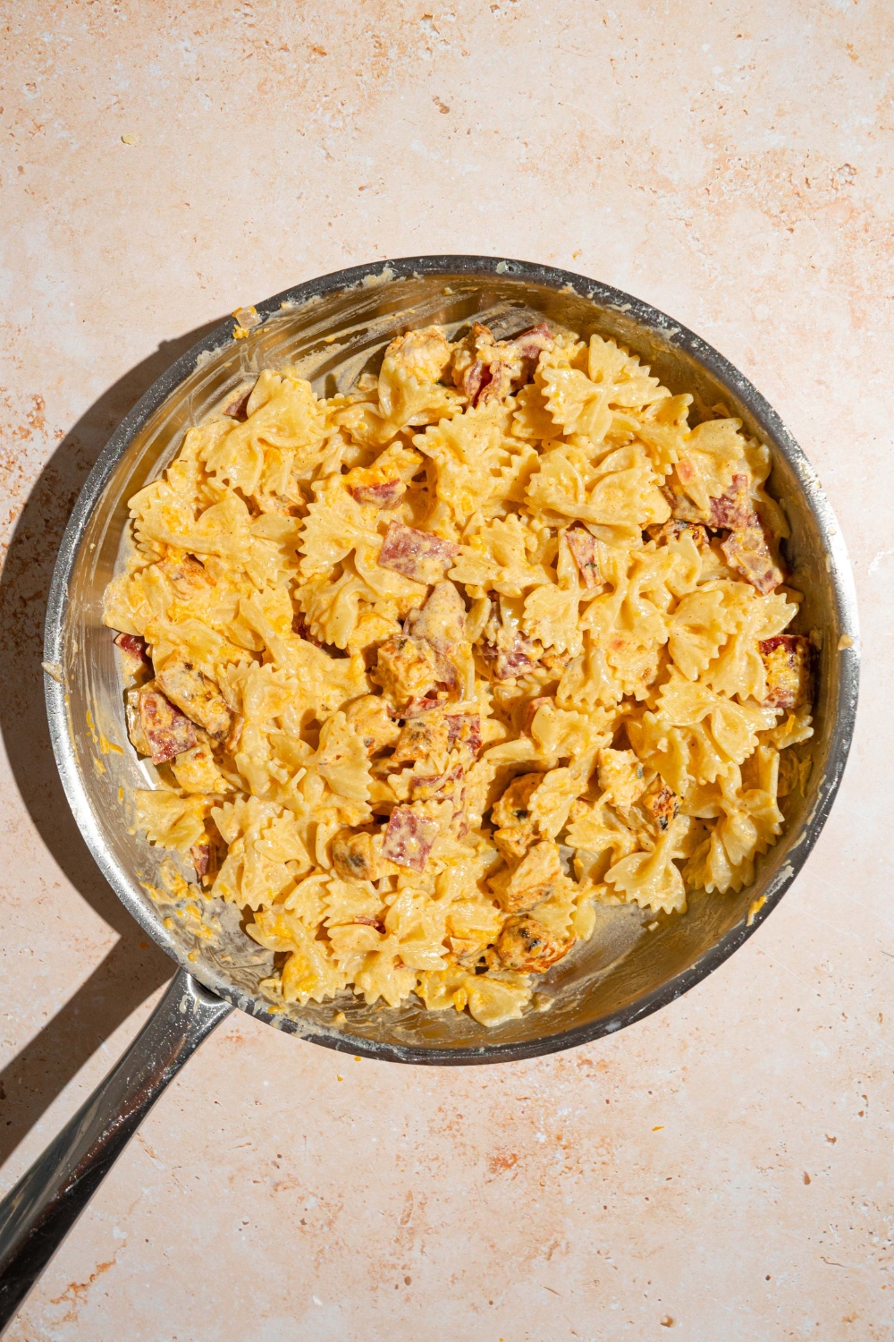 A skillet with chicken bacon ranch pasta tossed in a cream sauce. The skillet is on a tan counter.
