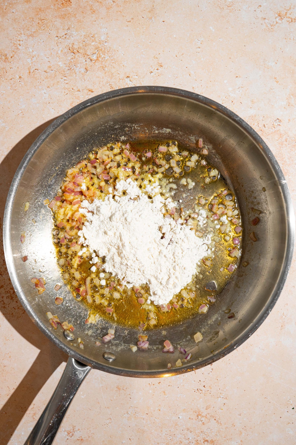 A skillet with melted butter and flour. The skillet is on a tan counter.