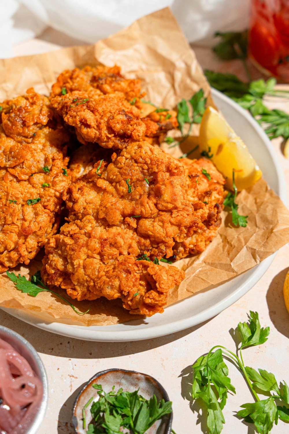 Part of a plate with three fried chicken thighs on top of it.