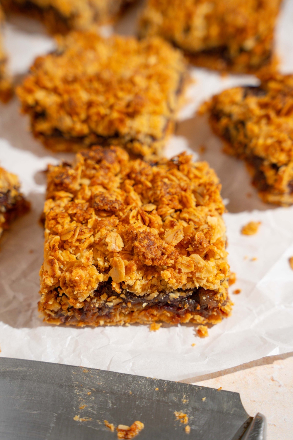 Several old fashioned date bars on a piece of parchment paper on a tan counter.