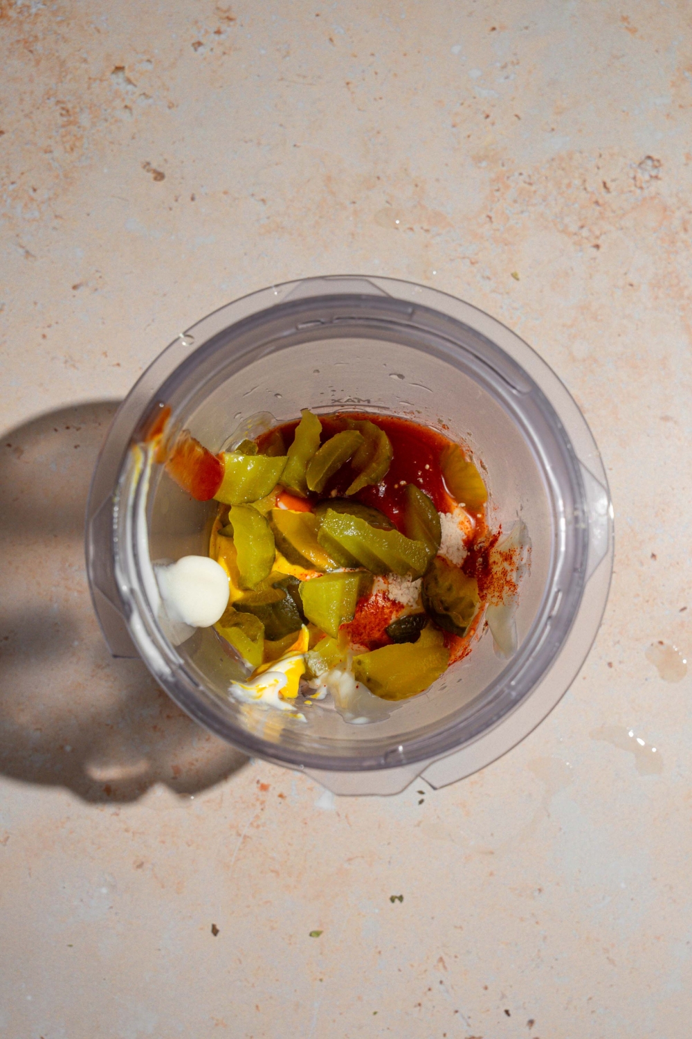 A glass blender jar with ingredients to make. Shake Shack sauce including ketchip, pickles, mayo, mustard, and seasonings.