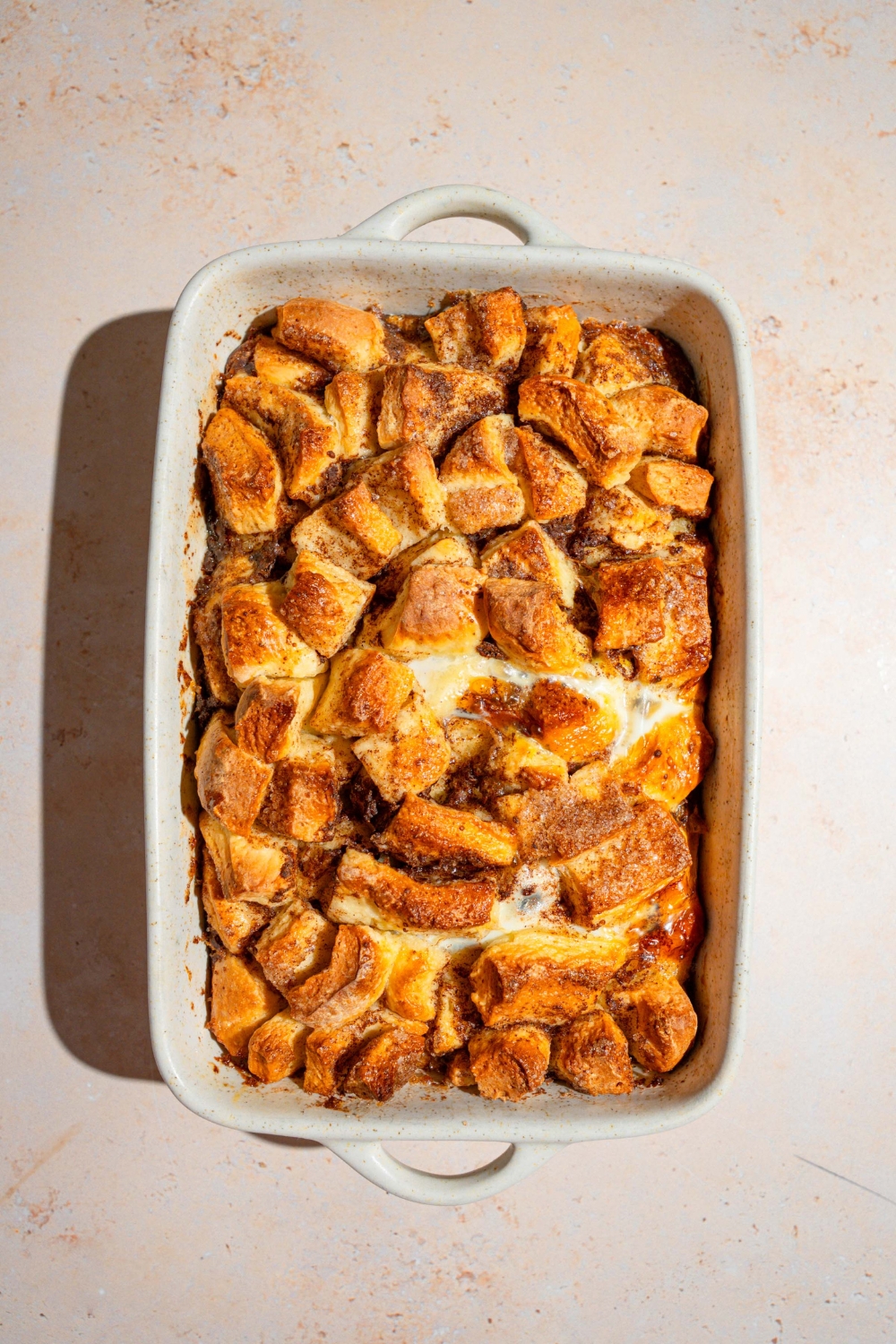 A baking dish of cooked cinnamon roll french toast. The dish is on a tan counter.