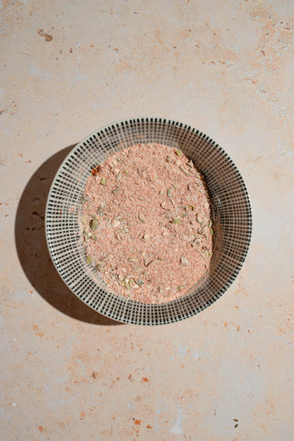 A ceramic bowl with a copycat Wingstop Louisiana rub mixture. The bowl is on a tan counter.
