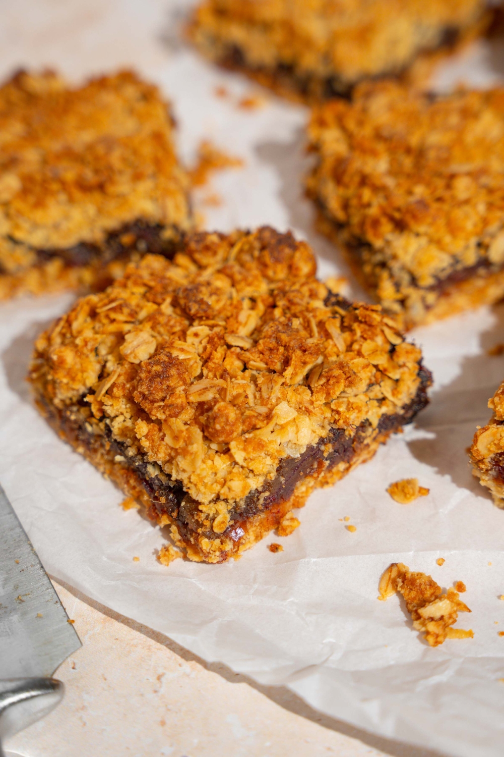 Several old fashioned date bars on a piece of parchment paper on a tan counter.