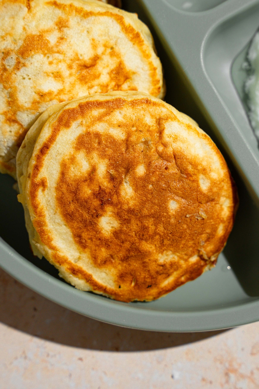 A kids plate with three 3 ingredient banana pancakes. The plate is on a tan counter.