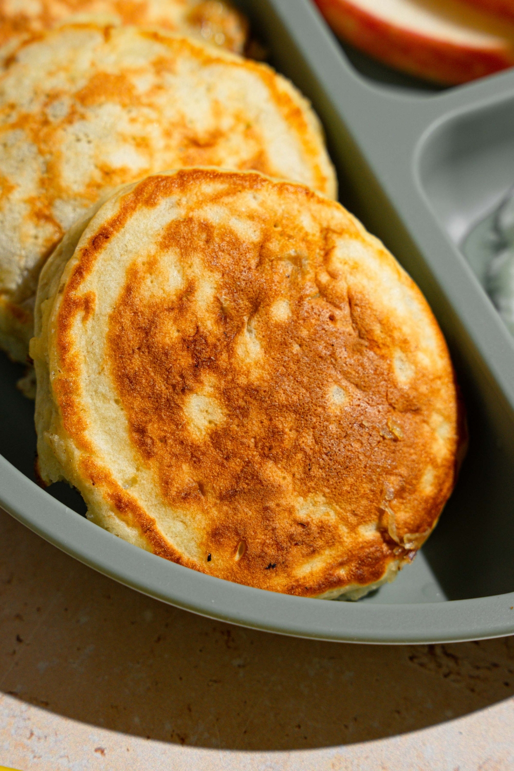 A kids plate with three 3 ingredient banana pancakes. The plate is on a tan counter.