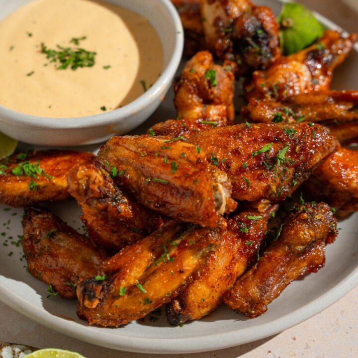 A bowl of baked wings tossed in Wingstop Louisiana rub. The bowl is on a tan counter.
