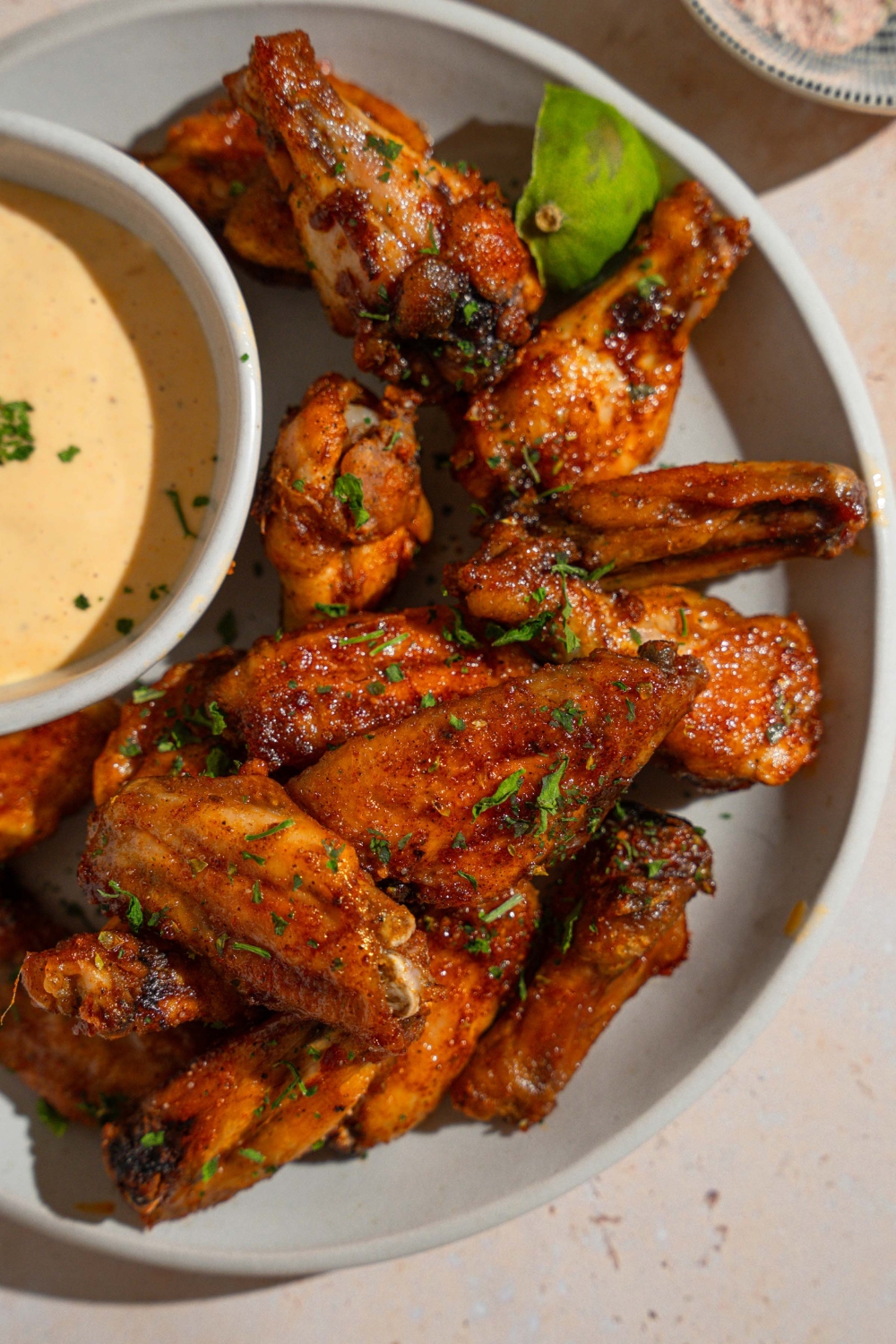 A bowl of baked wings tossed in Wingstop Louisiana rub. The bowl is on a tan counter.