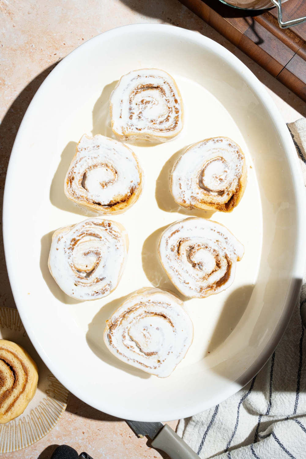 Six refrigerated cinnamon rolls in a baking dish with heavy cream in it.