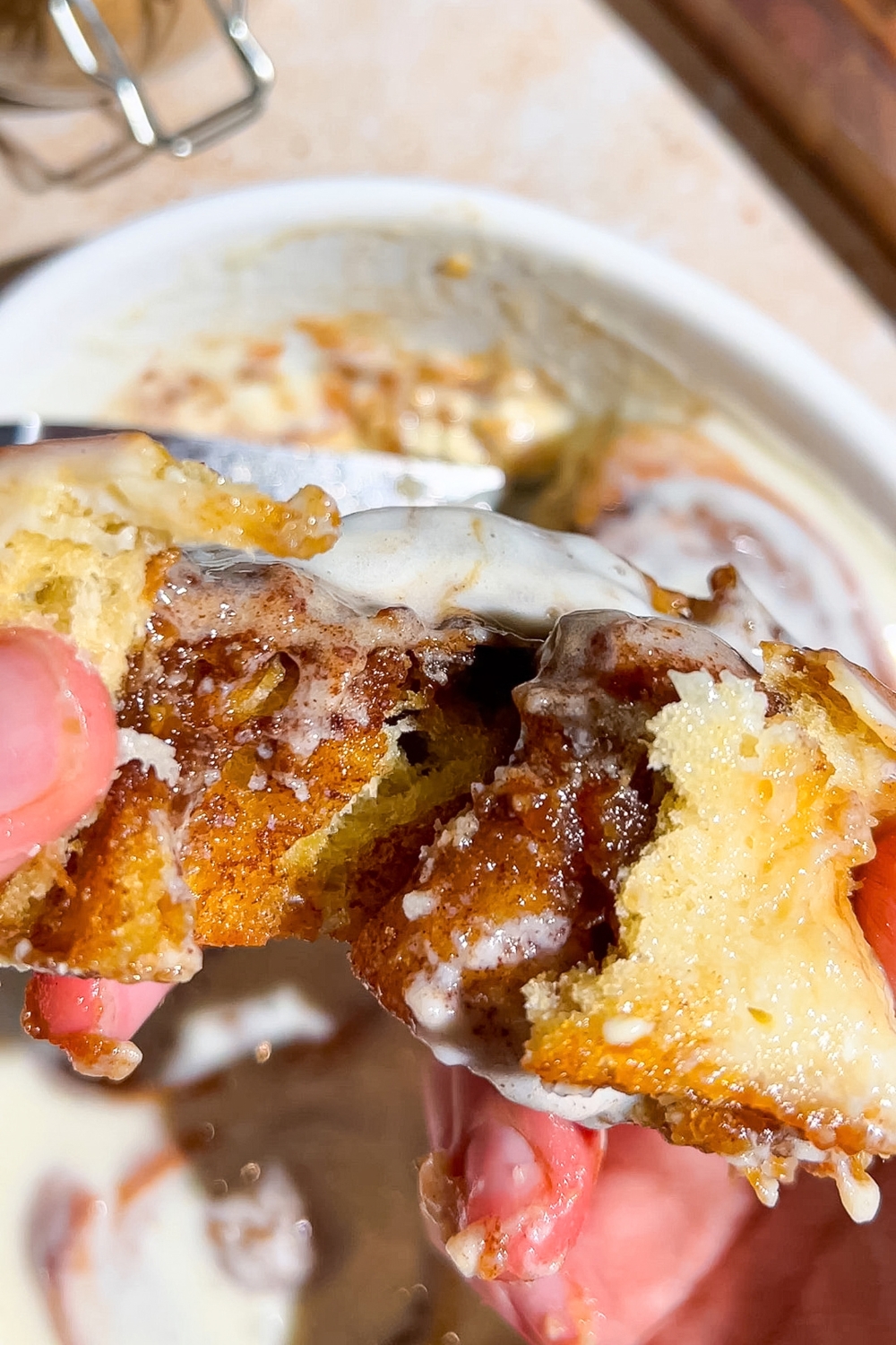 A hand breaking apart a viral cinnamon roll with the inside showing.