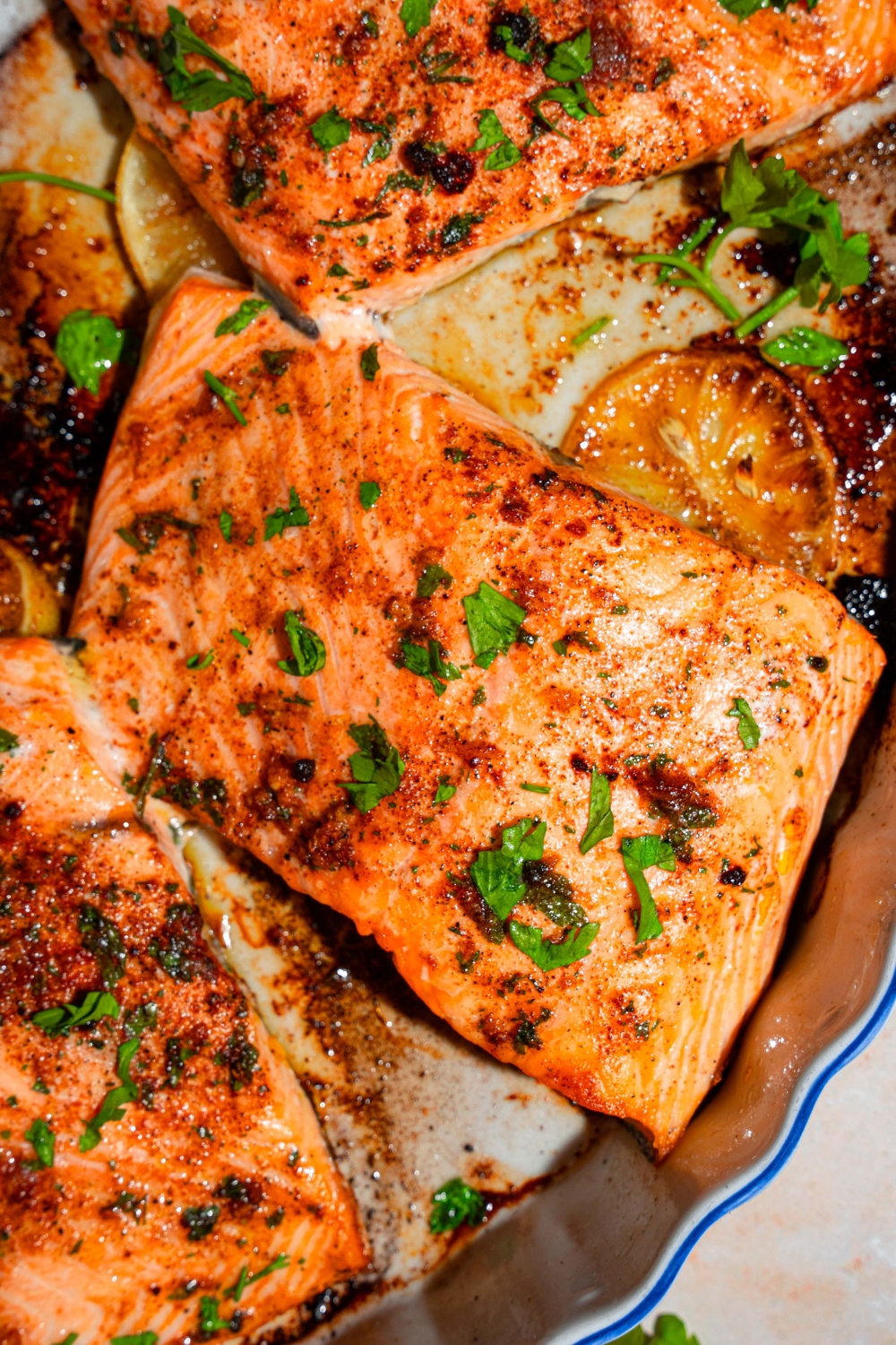 A baking dish with several pieces of baked Sockeye salmon garnished with fresh parsley.