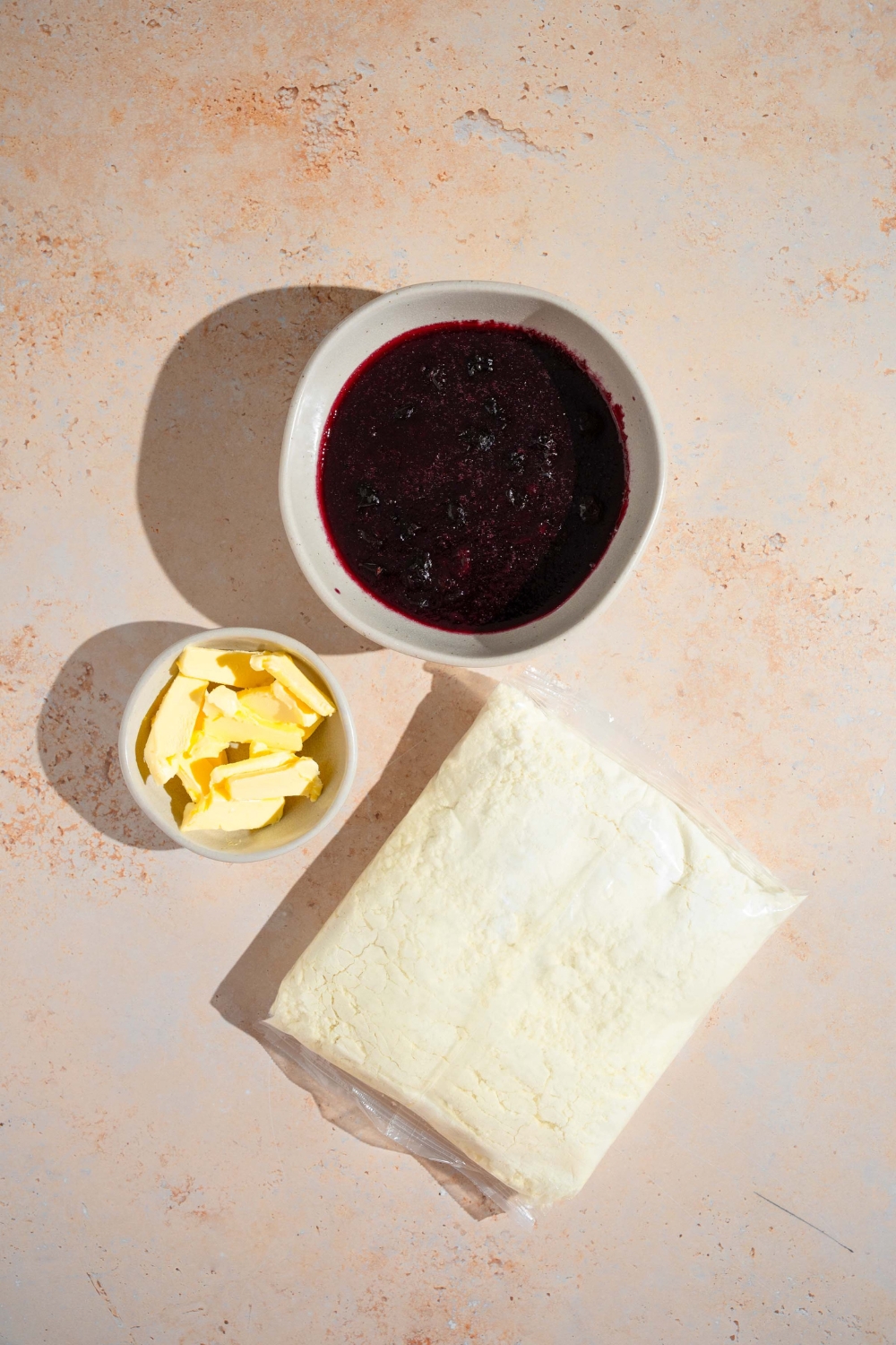 An overhead shot of ingredients for blueberry dump cake including blueberry pie filling, yellow cake mix, and butter.