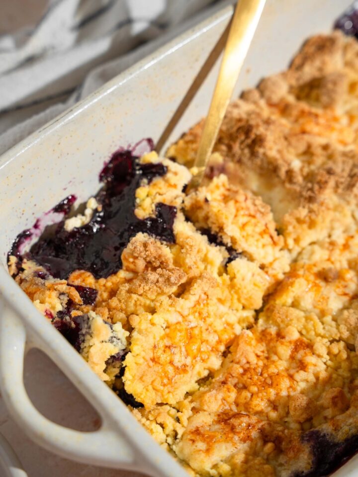 A baking dish with baked blueberry dump cake with a fork in the cake.