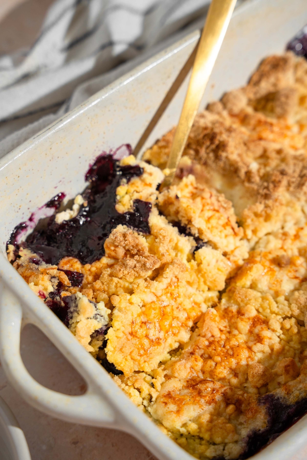 A baking dish with baked blueberry dump cake with a fork in the cake.
