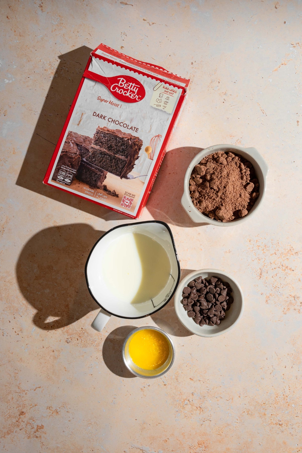 An overhead shot of ingredients to make chocolate dump cake including chocolate cake mix, instant chocolate pudding, chocolate chips, butter, and milk.