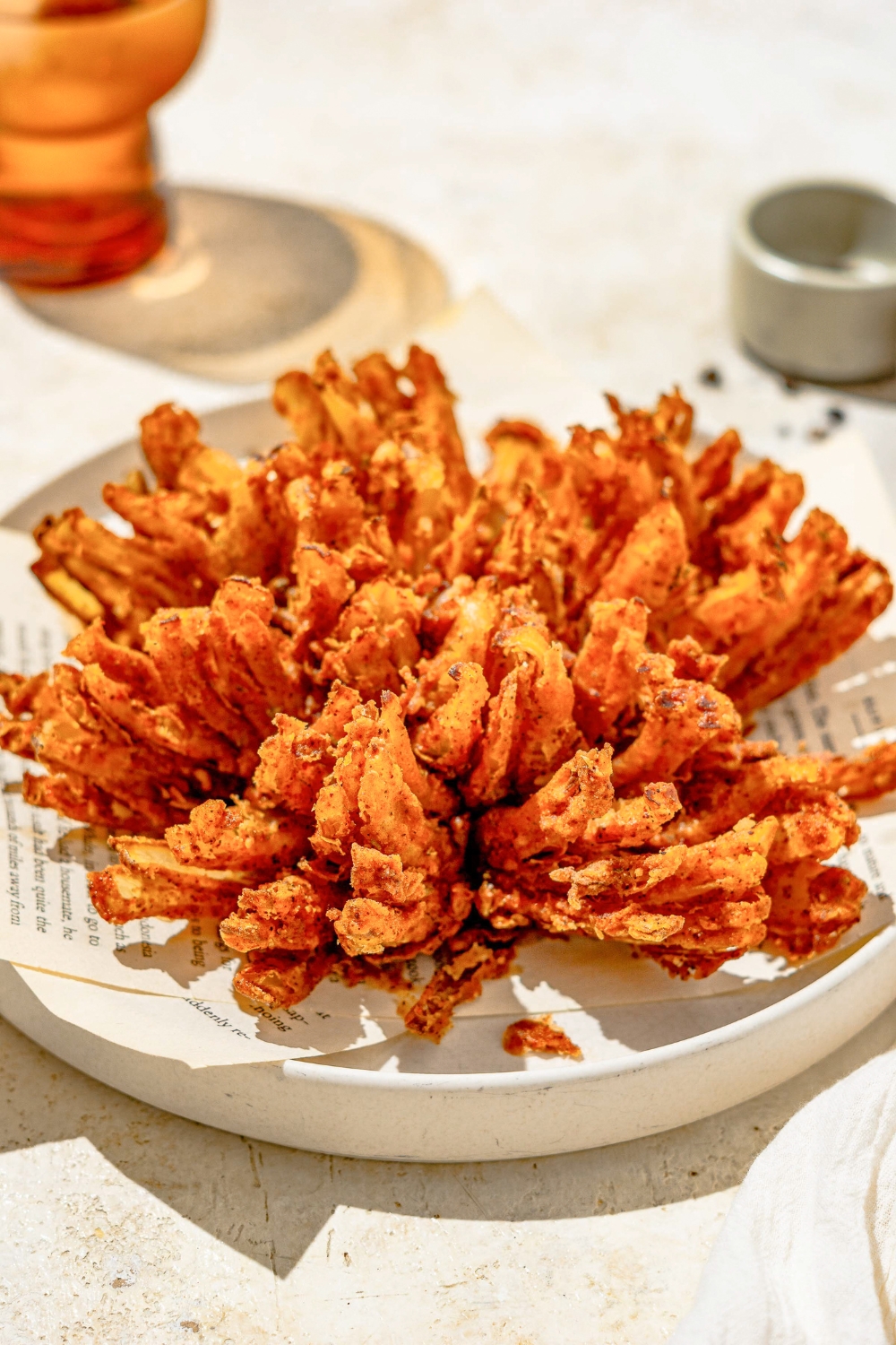 A copycat Outback bloomin onion on a white plate lined with paper. The plate is on a tan counter.