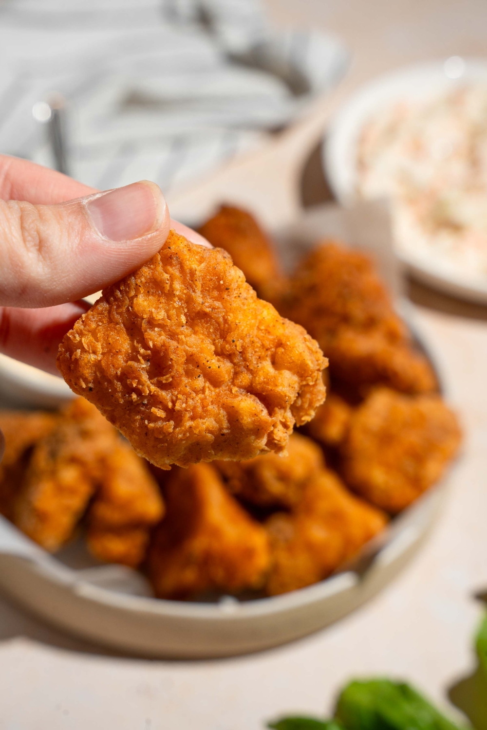A close up of a homemade Chick Fil A nugget with a plate of nuggets blurred in the background.