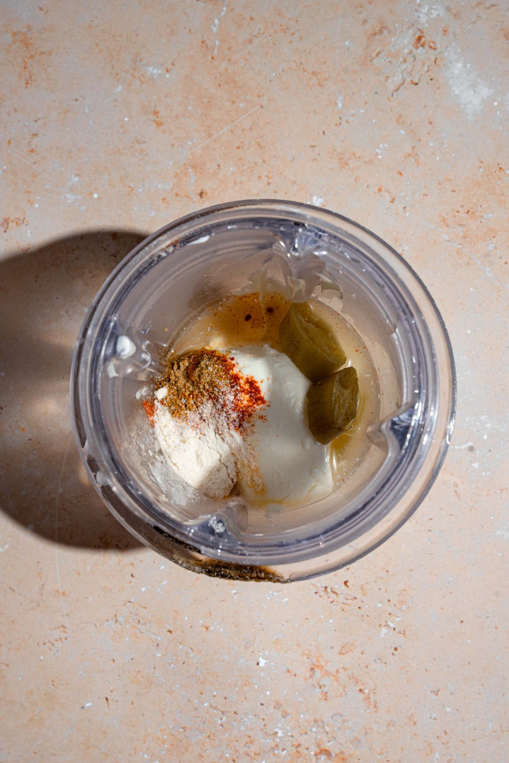 A glass jar with ingredients to make Taco Bell quesadilla sauce. The jar is on a tan counter.
