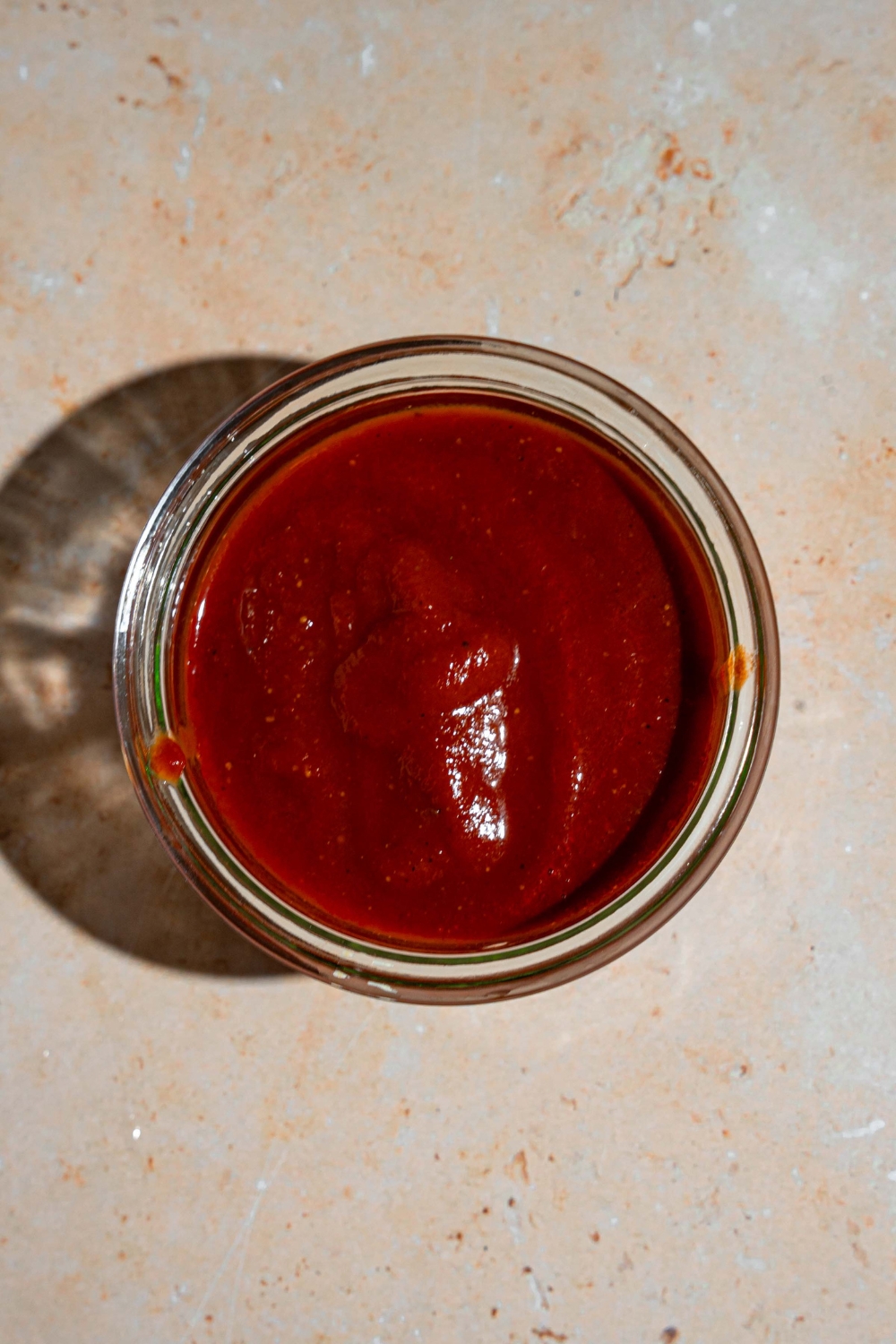 A glass jar with taco sauce. The jar is on a tan counter.