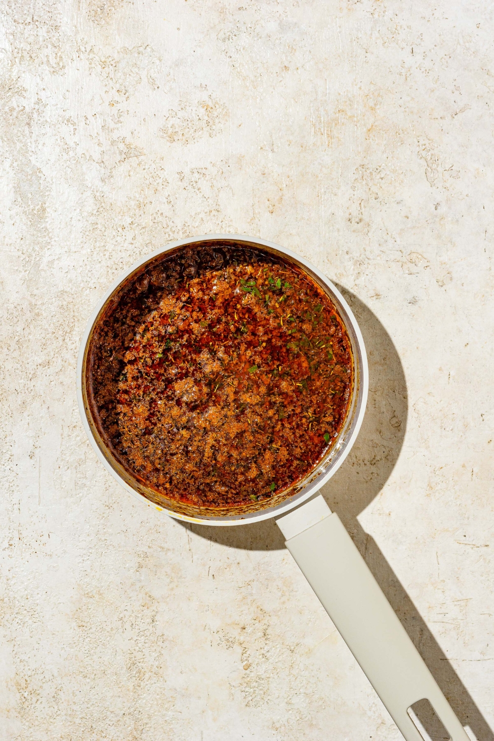 A saucepan with simmering cajun garlic butter sauce. The saucepan is on a tan counter.
