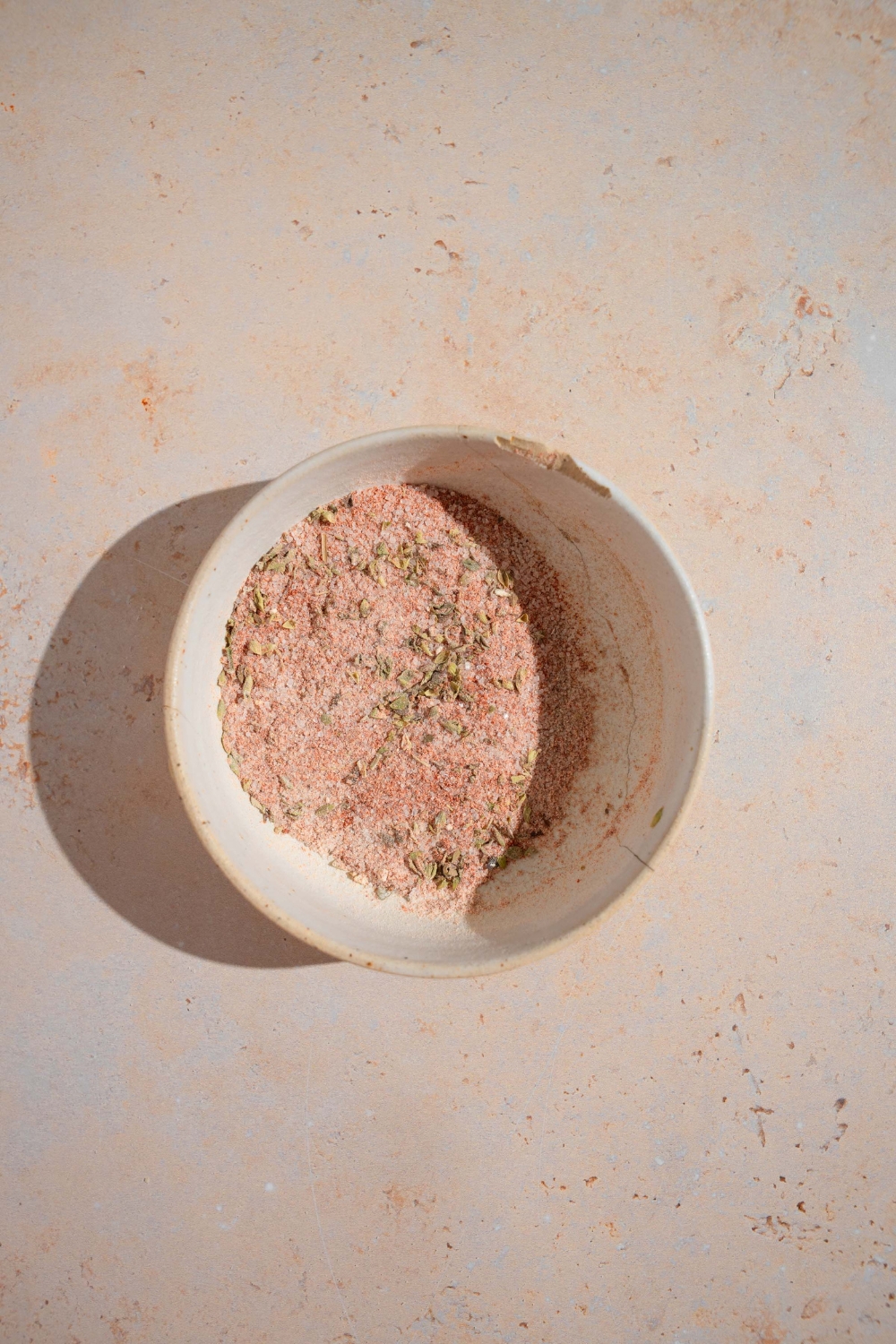 A small bowl of a Wingstop fries seasoning mixture. The bowl is on a tan counter.