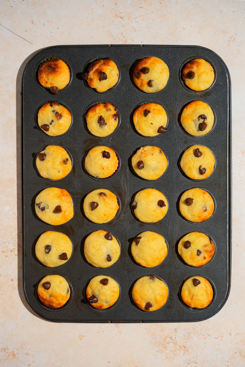A lined mini muffin baking sheet with baked copycat Little Bites chocolate chip muffins.